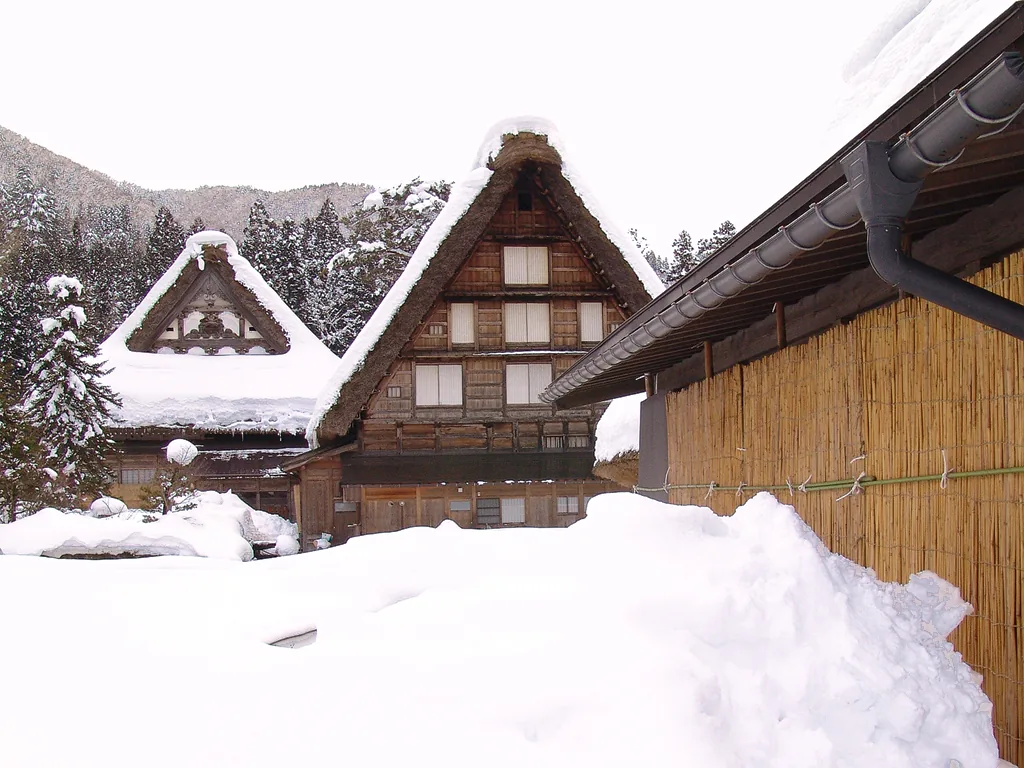 Snow-covered thatched gassho-style buildings of Myozenji temple in Shirakawa-go, with snow piled high in front