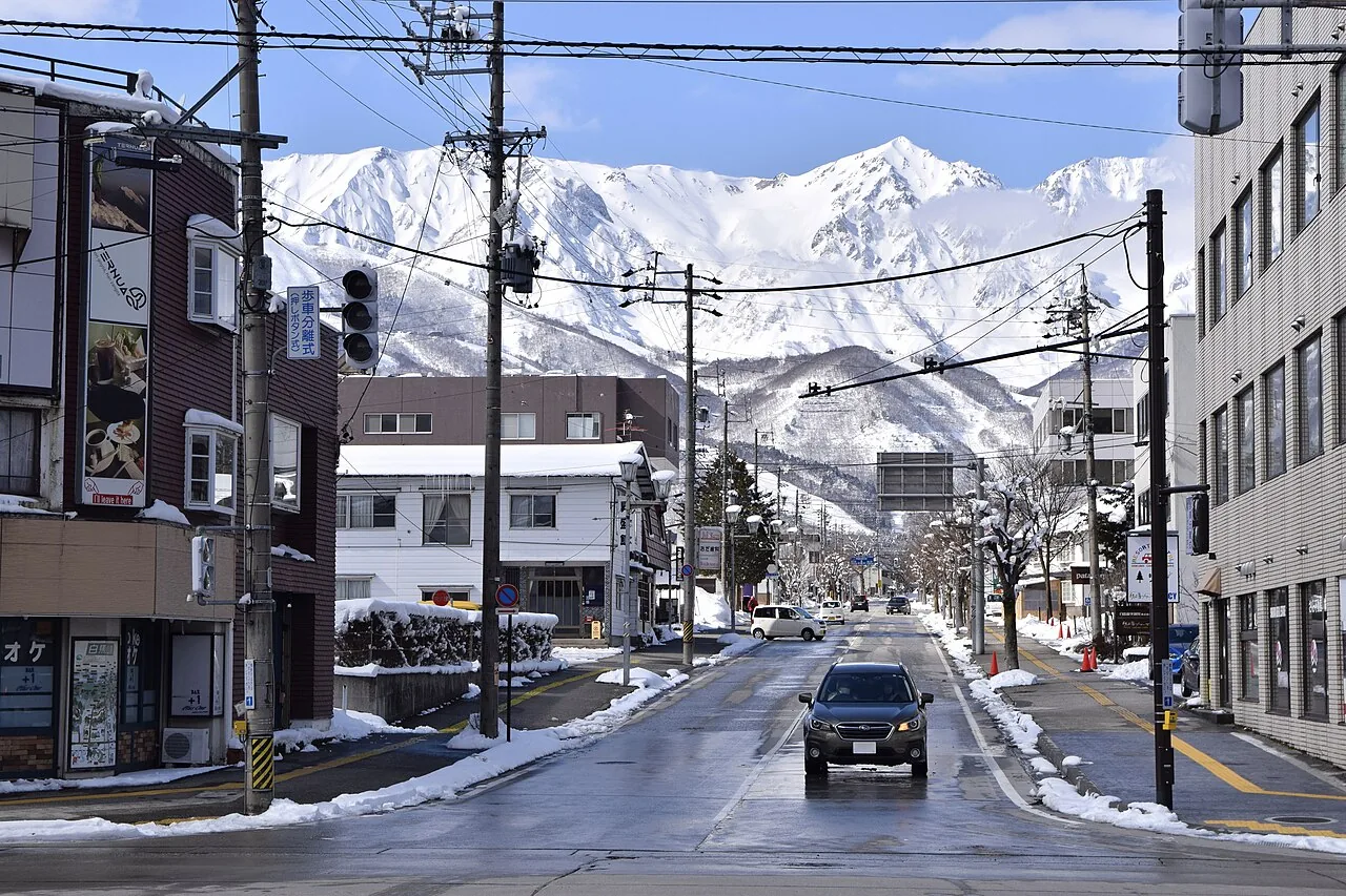 A snowy street in Hakuba village in February, with a white mountain peak at the end of the road