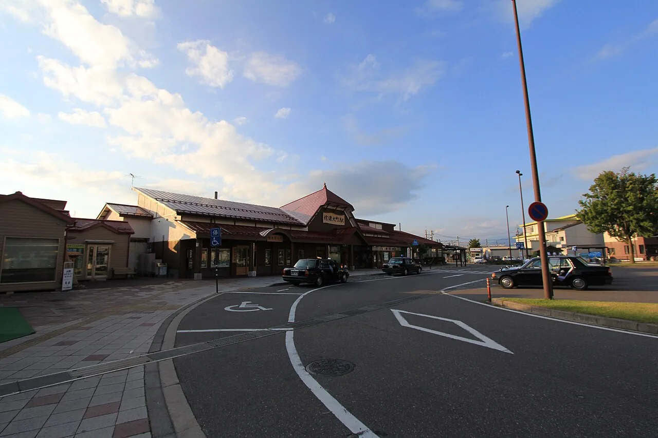The low wooden station building of Shinano-Omachi with taxis waiting outside