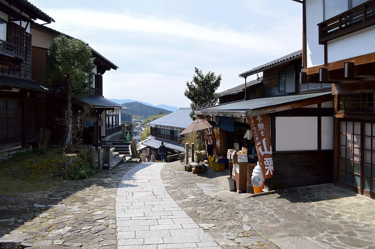 The stone-paved Nakasendo sloping down between wooden shops in Magome-juku