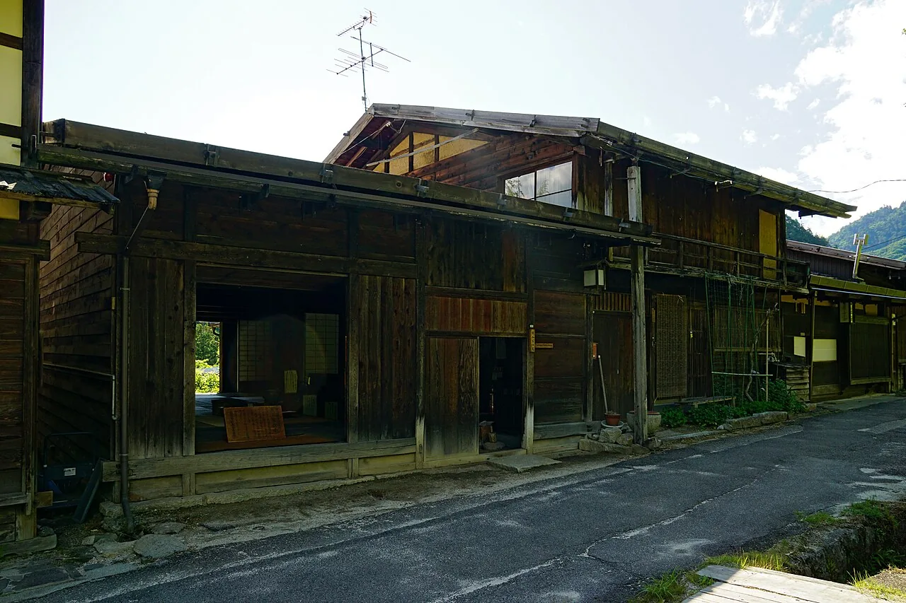The weathered wooden front of the Kumagai family house on the old road through Tsumago-juku, with an open room facing the street