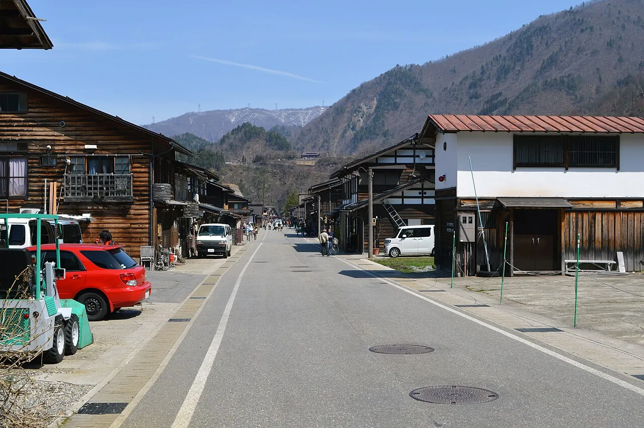 The main street through Ogimachi, Shirakawa-go, lined with wooden houses below forested hills